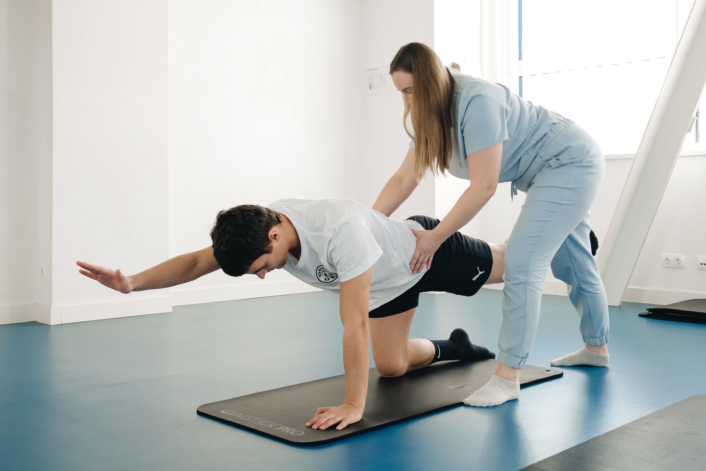 Physical therapist guiding a patient through a floor exercise